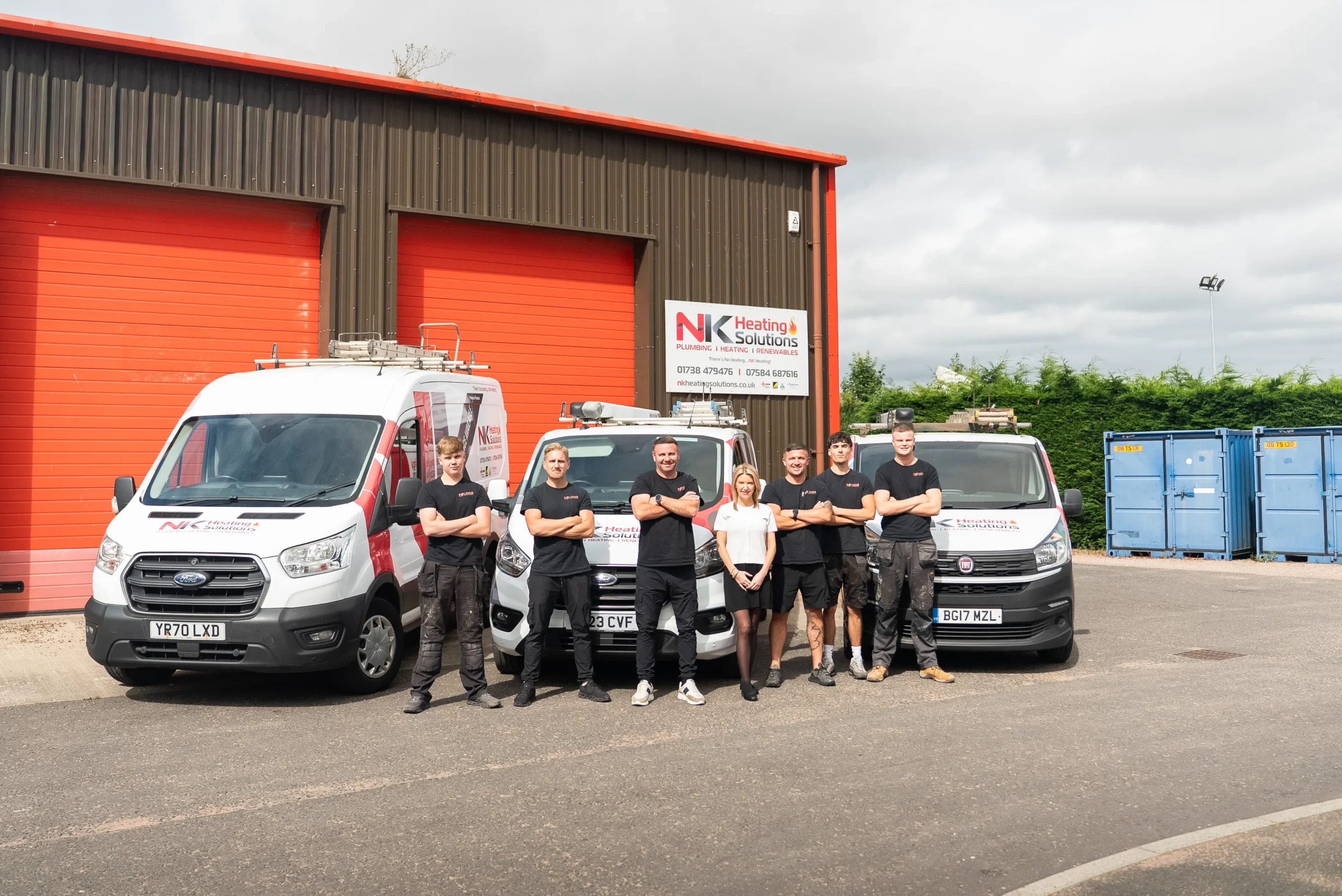 NK Heating Solutions Team Standing Infront of their Vans and Workplace