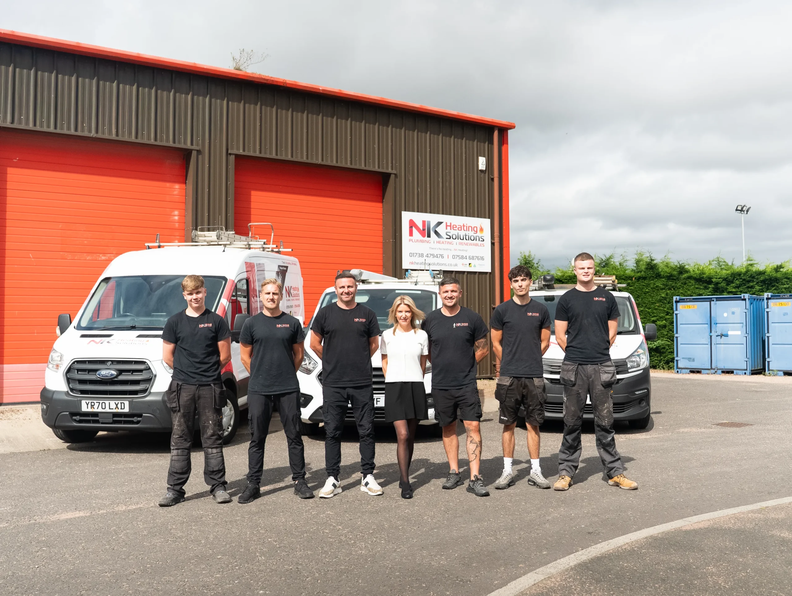 NK Heating Solutions Team Standing Infront of their Vans and Workplace
